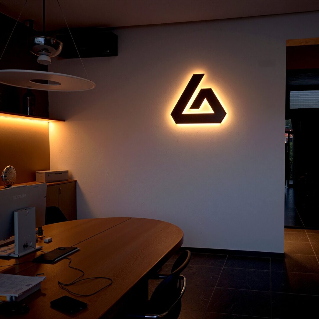Logo nero a parete con luce calda alle spalle in un ufficio, di sera