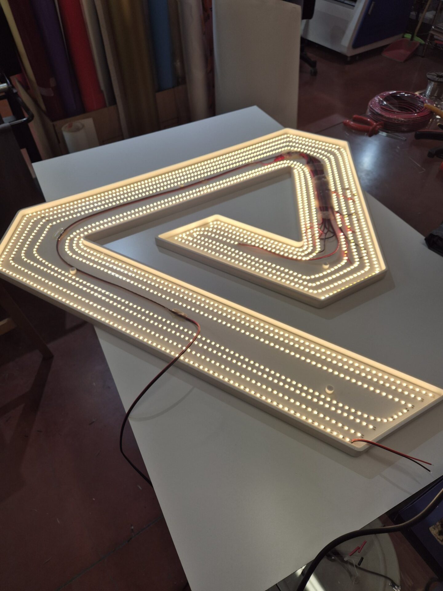 Insegna luminosa con strisce di luce in lavorazione nel laboratorio