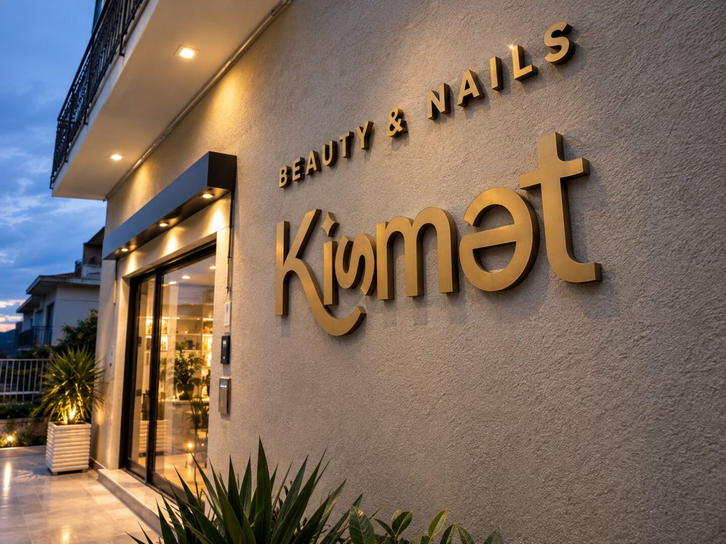 Scritta Kismet Beauty & Nails in lettere dorate in rilievo sulla facciata, di sera