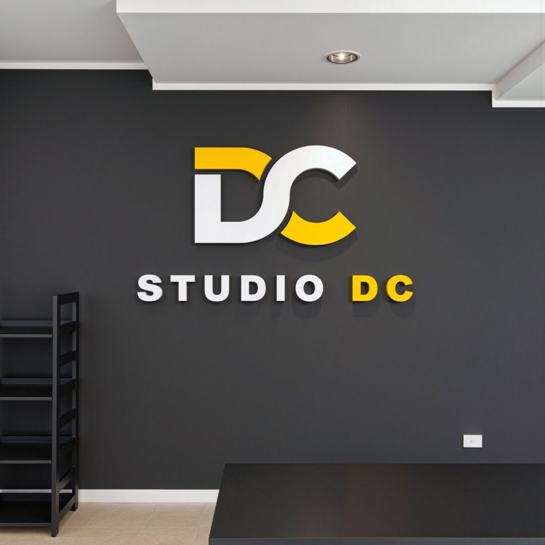 Logo Studio DC in rilievo bianco e giallo sulla parete scura della sala