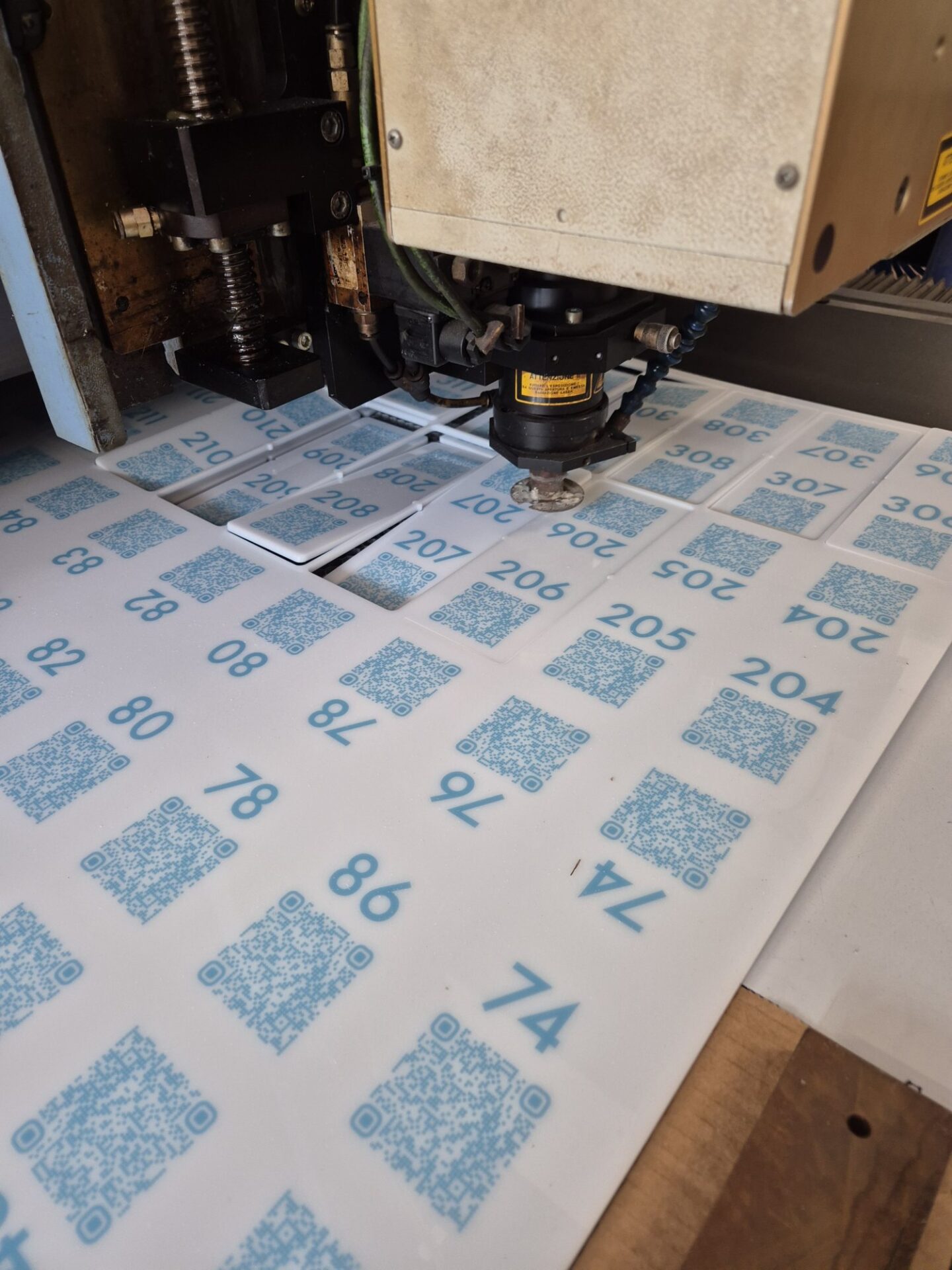 Testa del laser che taglia targhette con codice QR nel laboratorio